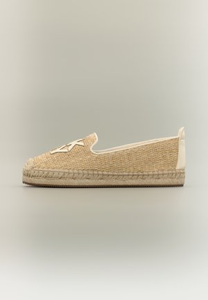 Pantof espadrile bej împletit cu talpă de iută, margine albă și un design stilizat cu litere albe cusute pe partea superioară din față.