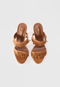Brown suede high-heeled sandals with multiple fringe accents, open toe design, and strap details; features a logo on the insole.