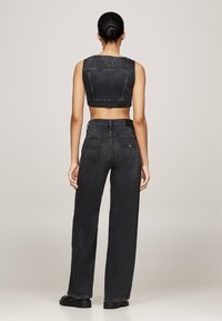 Svart denim crop top og vide jeans, med rå søm, fem-lomme design og baklapp. Glatt tekstur med minimal detaljer.