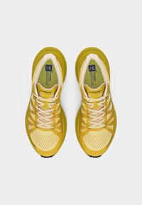 Ζευγάρι κιτρινοκρεμ Veja Condor 3 παπούτσια τρεξίματος, φωτογραφημένα από πάνω σε λευκό φόντο, με λεπτομερείς κορδόνια και πλέγμα στα πάνω μέρη.