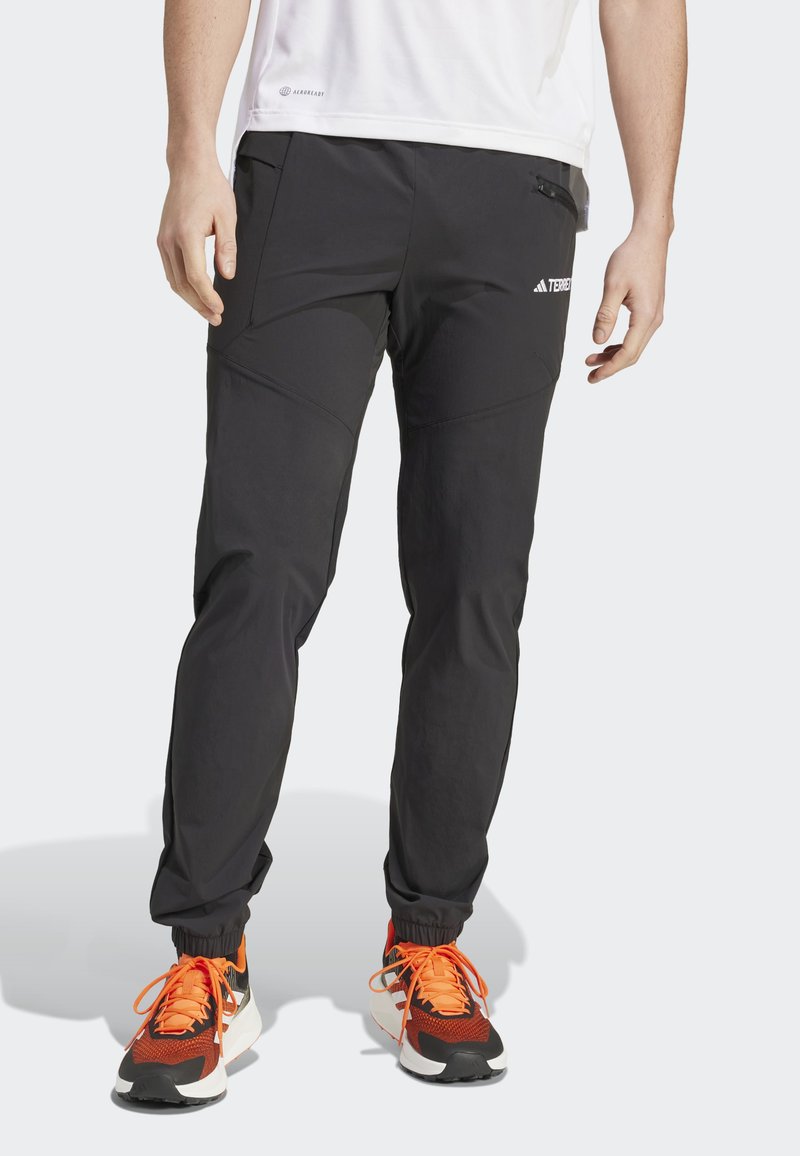 Czarne sportowe spodnie o tapered design, z zamykanymi na zamek kieszeniami i elastycznymi mankietami. Wykonane z lekkiego materiału, idealne do aktywności fizycznej.