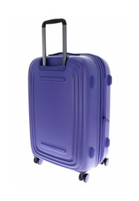 Valise rigide violette avec design strié, poignée rétractable unique et quatre roues noires pour une mobilité facile. Compartiment principal zippé.