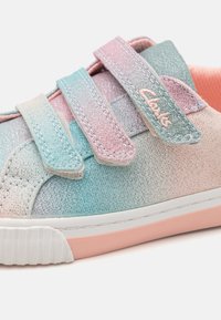 Velcro sneakers, mis sisaldab pastellvärvidega roosa ja akvaprae seostust sädelevas tekstuuris, valge tallaga ja diskreetse brändi logoga rihmal.