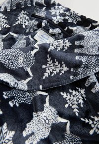 Fleece-morgonrock med marinblå bakgrund, vita snöflingor och djurmönster. Mjuk textur, vikbar design och vård etikett synlig.