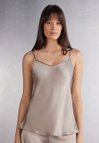 Satin camisole in een muted beige tint, met verstelbare dunne bandjes en een V-halslijn. Gladde textuur met een subtiele glans.