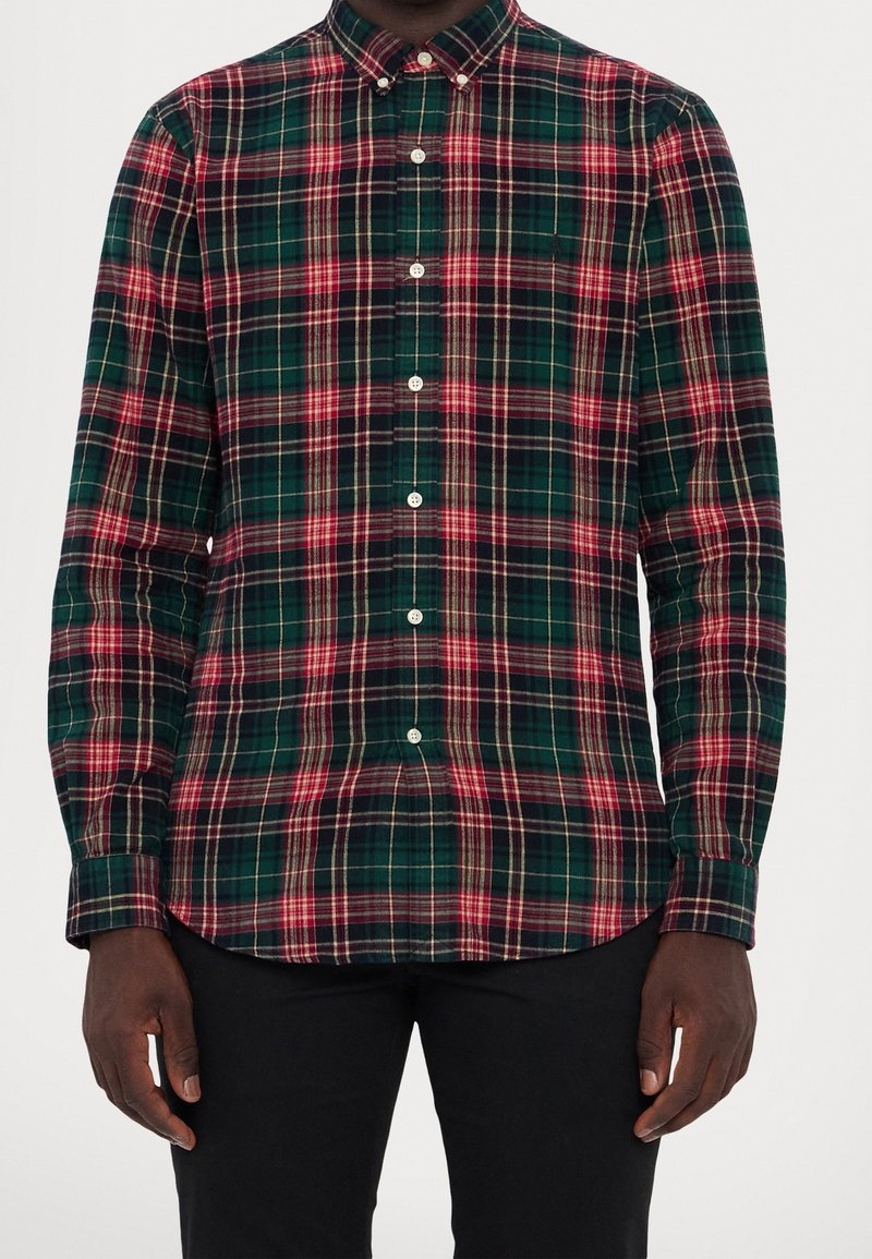 Camicia a quadri verde e blu navy con accenti rossi e crema, maniche lunghe, colletto button-down e bottoni sul davanti. Tessuto in cotone.