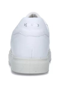 Sneaker bianco con tomaia in sintetico liscio, forma rotonda, tacco imbottito e logo metallico discreto vicino alla parte superiore. Suola in gomma piatta.