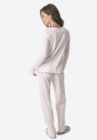 Ensemble de pyjama blanc à rayures avec de petits motifs floraux bleus et rouges, avec des manches longues, une coupe décontractée et des bords festonnés sur les ourlets.