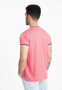 Rød t-shirt med korte ærmer i meleret tekstur, med sort-hvide stribede detaljer på kraven og ærmespidserne.