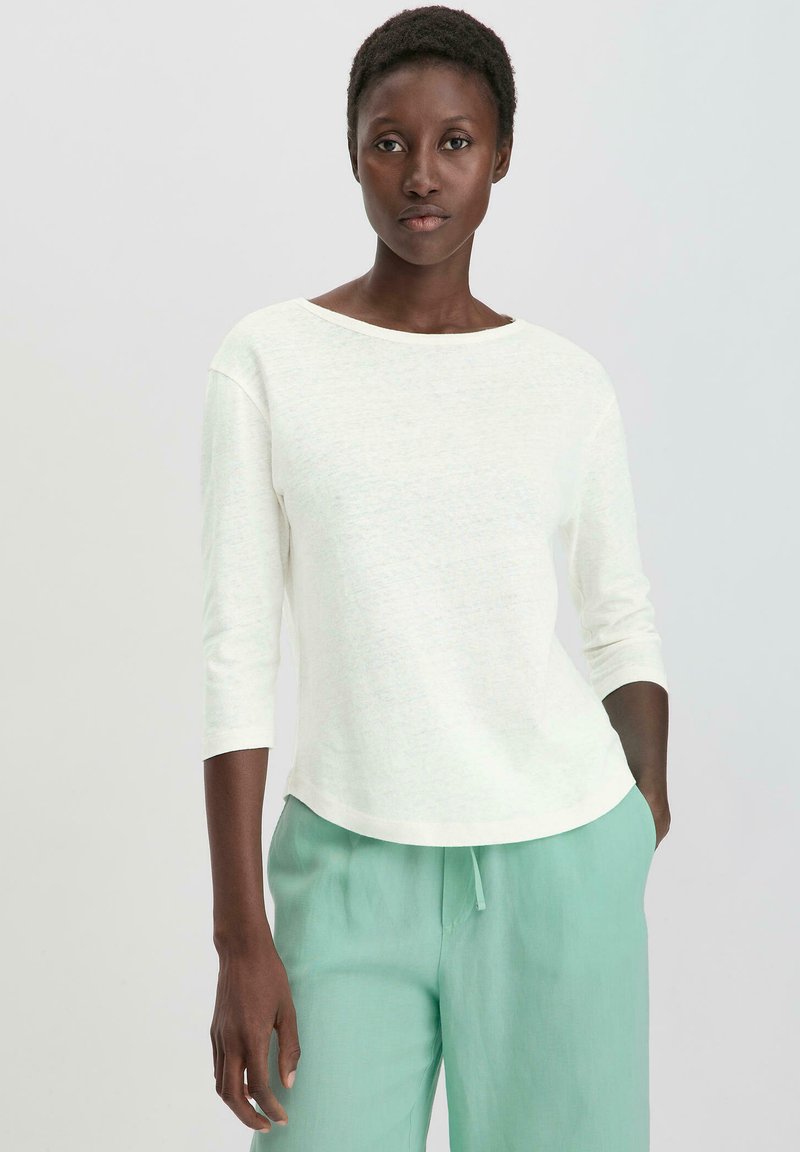 Leichtes, cremefarbenes Hemd mit 3/4-Ärmeln, rundem Halsausschnitt und einer weichen Textur, kombiniert mit lockeren, mintgrünen Hosen.