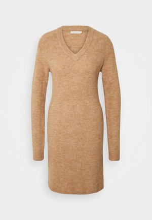 Robe en tricot beige avec un décolleté en V, des manches longues et une texture côtelée. Se termine au milieu de la cuisse, présentant une silhouette simple et ajustée.
