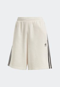 Krémové žebrované šortky s volným střihem, které mají černé boční pruhy a logo Adidas na dolní levé nohavici. Elastický pas.