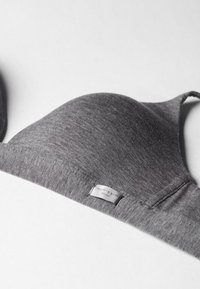 Sostenedor gris de tela elástica con copas moldeadas y una banda suave. Presenta una etiqueta con el logo etiquetada "intimissimi" para la identificación de la marca.