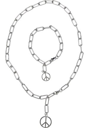 Sølv kædesmykke og armbåndssæt med stort leddesign, med et fredssymbol vedhæng på hver del. Glat metallisk finish.