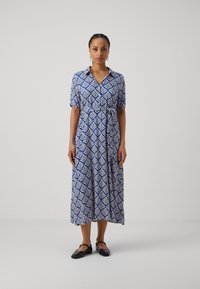 Blue and white patterned shirt dress with short sleeves, waist tie, and relaxed fit. Features a leaf design and falls to mid-calf.