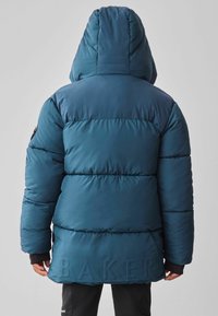 Doudoune bleue avec capuche, dotée de sections matelassées, d'accents noirs et du mot "BAKER" embossé dans le dos. Texture lisse et design isolé.