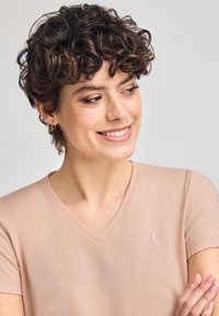 Ljusrosa bomulls T-shirt med V-hals och korta ärmar, samt en liten broderad logotyp på bröstet. Mjukt material med en avslappnad passform.