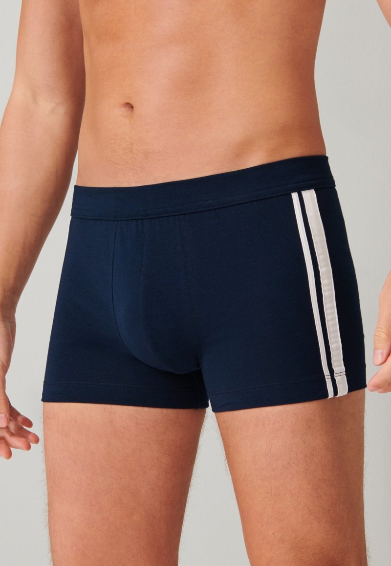 Mörkblå boxerkalsonger i mjuk bomull med en tight passform, med vita sidostickningar och en slät midjeresår. Ingen synlig branding eller mönster.