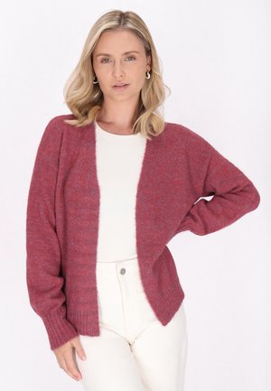 Cardigan tricotat roșu cu o croială lejeră, deschis în față și cu manșete cu nervuri. Purtați peste un top de culoare deschisă, asortat cu pantaloni albi.