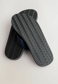 Black flip-flops with a textured wavy sole and navy fabric straps. The straps have a subtle pattern and are outlined with white accents.