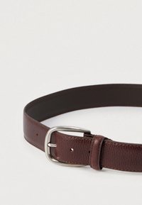 Pruun nahast vöö, millel on tekstuuriga pind, hõbedane metallist pandel ja reguleeritavad augud kinnitamiseks. Ümar kuju ja sile sisekülg.