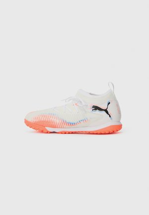 Chaussure de sport blanche avec une surface texturée, semelle orange vif et accents bleus. Présente un design montante et un logo noir sur le côté.