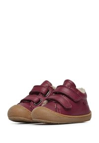 Scarpe in pelle rossa con due fasce in velcro, suola in gomma marrone con texture e imbottitura soffice attorno alla caviglia. Design a punta arrotondata.