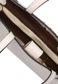 Beige Leder-Shopper mit schwarzen Akzenten, ausgestattet mit einem Reißverschluss-Innenfach und goldenen Beschlägen. Glatte Textur mit minimalistischem Design.
