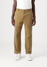 Chino khaki din bumbac ușor, cu croială dreaptă, închidere cu nasture și o textură netedă, asortat cu adidași albi.