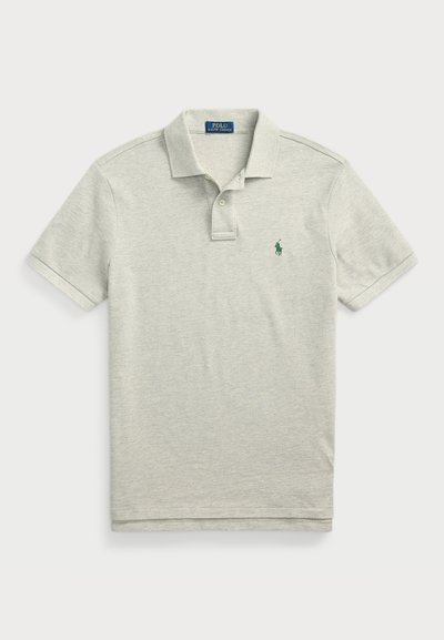Polo de cor cinza claro feito de algodão macio, com uma pala de três botões e um pequeno logótipo verde no lado esquerdo do peito. Mangas curtas.