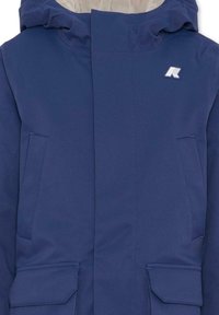 Giacca impermeabile blu navy con cappuccio, dotata di due tasche frontali angolate, un logo bianco e una texture liscia. Cuciture visibili.