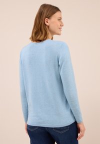 Hellblauer Pullover aus weichem Material. Verfügt über einen runden Ausschnitt und lange Ärmel. Rippstrickverarbeitung an den Bündchen und am Saum. Der Schnitt ist leicht lässig.
