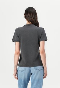 T-shirt grigio a maniche corte in cotone, con collo rotondo e taglio rilassato, mostrato da dietro con dettagli di cucitura visibili.