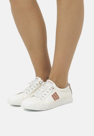 Zapatillas de lona blancas con punteras redondas, que cuentan con detalles en marrón claro, diseño de cordones y un logotipo en los lados exteriores.