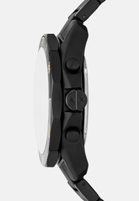 Črni ura s šestkotno ohišjem, tremi gumbi in zlatimi detajli. Ima teksturiran pas in prozoren, okrogel stekleni obraz.