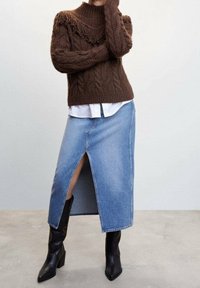 Pull en maille cable marron avec col montant ; jupe en denim bleu clair avec fente latérale ; bottines noires à talons carrés. Textures lisses.