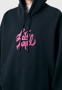 Felpa nera con cappuccio e tasca frontale, caratterizzata da una grafica rosa. Realizzata in tessuto dalla texture morbida e con coulisse regolabili sul cappuccio.