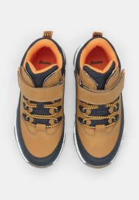 Zapatillas marrones y marinas con un upper texturizado, tira de velcro y cordones amarillos en contraste, con una suela de goma blanca.
