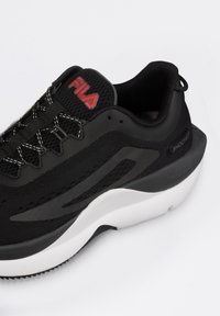 Scarpa da corsa nera con tomaia in rete, suola bianca e dettagli rossi. Presenta un design del laccio intricato e un marchio distintivo sulla linguetta.