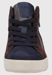 Zapatillas altas de ante marrón y marino con suela de goma texturizada, puntera redondeada y cordones marinos. Cuenta con un cierre de cremallera y una marca destacada.