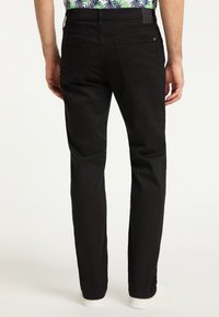 Czarne dżinsy o prostym kroju, fakturowana tkanina, dwie tylne kieszenie i widoczne szwy. W połączeniu z białymi trampkami.