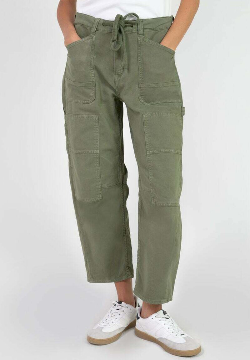 Pantalones cargo verdes de algodón, con cintura elástica y cordón, múltiples bolsillos y un corte holgado, combinados con zapatillas blancas.