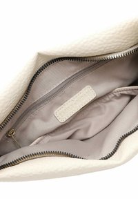 Witte textuur leren tas interieur met een beige voering, voorzien van een ritsvak en een label met de tekst "EMILY & NOAH." Zwarte rits tanden zichtbaar.