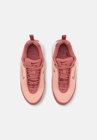 Sapatilhas Nike Air em rosa claro e vermelho. Parte superior em malha, forma arredondada, amortecimento de ar visível, sola texturizada e sistema de atacadores contrastante.