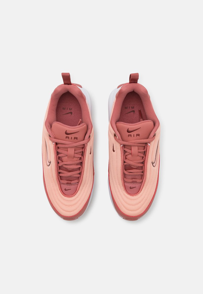 Sapatilhas Nike Air em rosa claro e vermelho. Parte superior em malha, forma arredondada, amortecimento de ar visível, sola texturizada e sistema de atacadores contrastante.