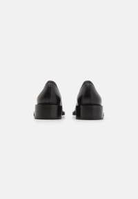 Black leather shoes with a smooth texture, rounded toe, low block heel, and minimal stitching detail, viewed from the back.