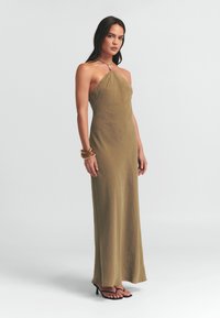 Olijfgroene, strapless maxijurk gemaakt van een gladde, lichte stof. Heeft een flatterende A-lijn silhouet, met een subtiele glans en geen zichtbare patronen.