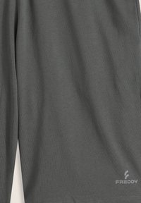 Camiseta deportiva gris con una textura suave, mangas cortas y un logo sutil en el dobladillo para la marca. Diseño ligero y casual.