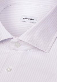 Gros plan d'une chemise blanche à fines rayures diagonales, boutons blancs et une étiquette à l'intérieur du col indiquant "seidensticker."