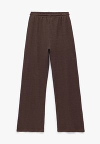 Bruine, wijde broek gemaakt van een gestructureerde stof met een elastische tailleband. Het ontwerp heeft een losse pasvorm en geen zichtbare sluitingen.